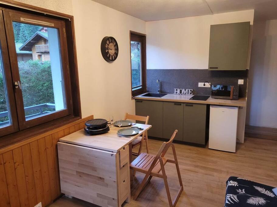 eine Küche mit einem Holztisch sowie einem Tisch und Stühlen in der Unterkunft Studio Châtel rénové et lumineux in Châtel