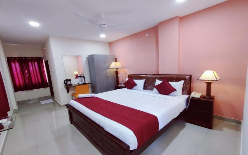 a bedroom with a large bed with red and white sheets at Classic Hotel in Shamshabad