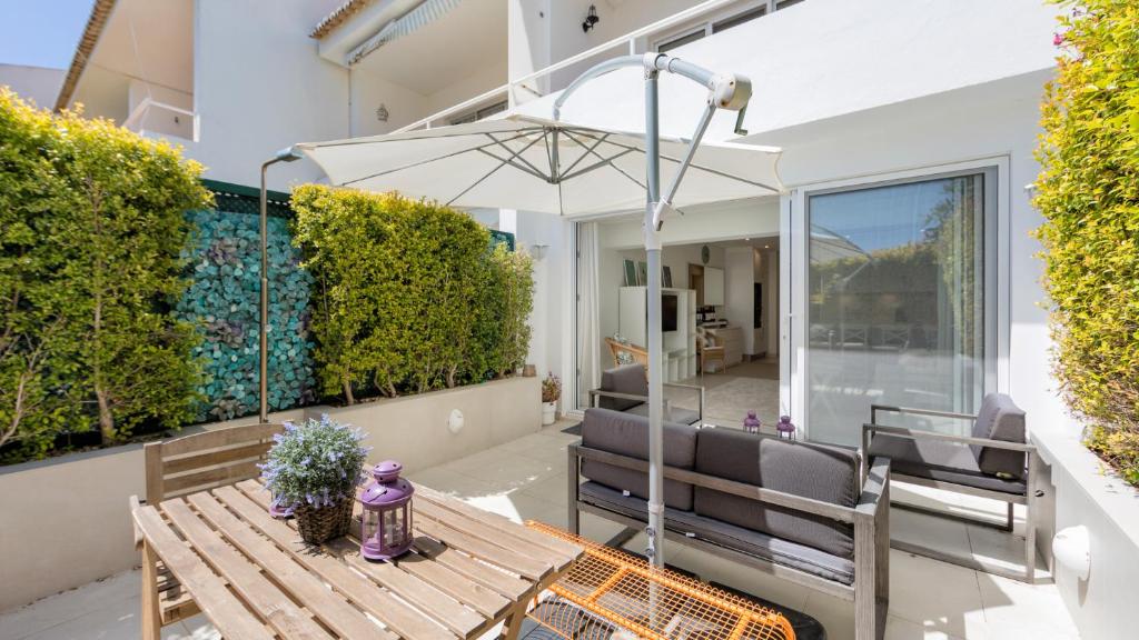 une terrasse avec une table, des chaises et un parasol dans l'établissement Keiko, à Almancil