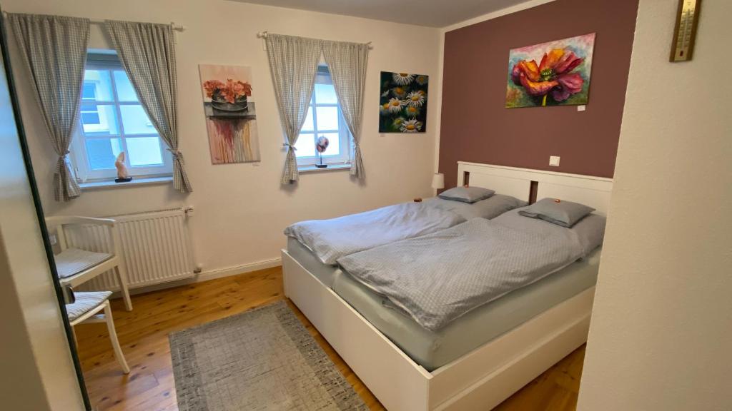 a bedroom with a bed and two windows at Ferienhaus Schlupfwinkel in Bad Neuenahr-Ahrweiler