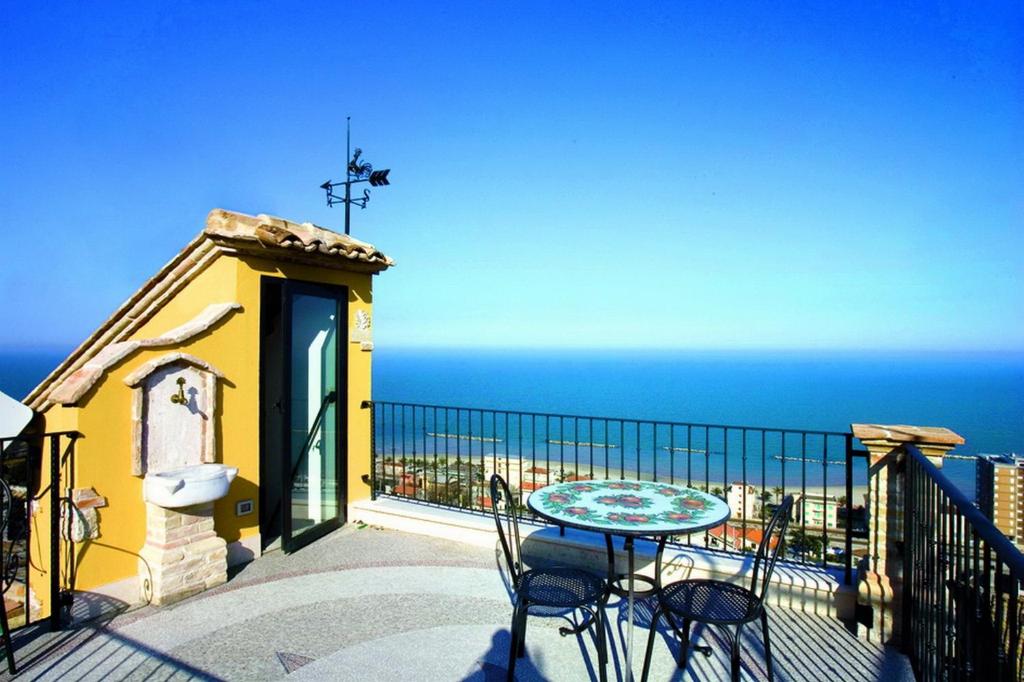 balcón con mesa, sillas y vistas al océano en B&B La Torretta sul Borgo en Grottammare