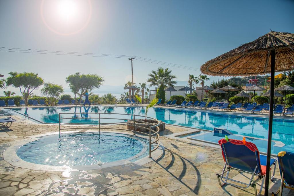 a pool with chairs and an umbrella at a resort at Semiramis Village in Hersonissos