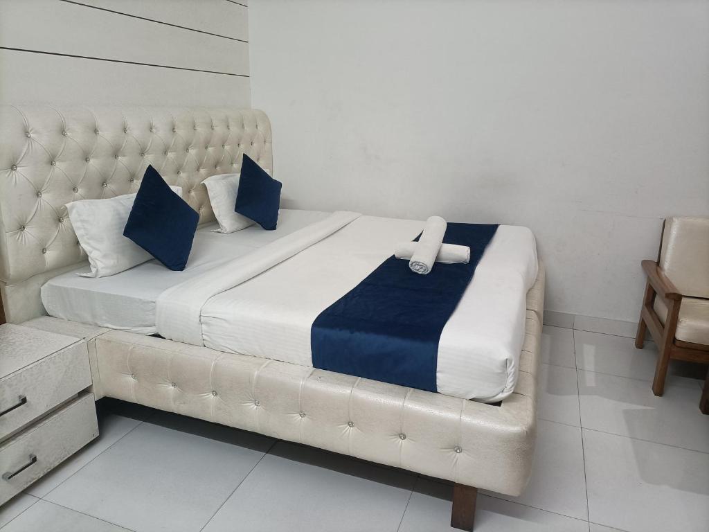 a bed with blue and white sheets and blue pillows at Hotel Midtown in Haridwār