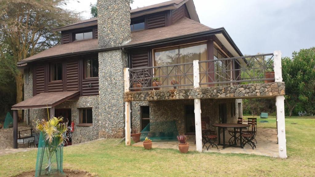 a large house with a deck and a chimney at Kwezi Cottage at The Great Rift Valley Lodge & Golf Resort Naivasha in Naivasha