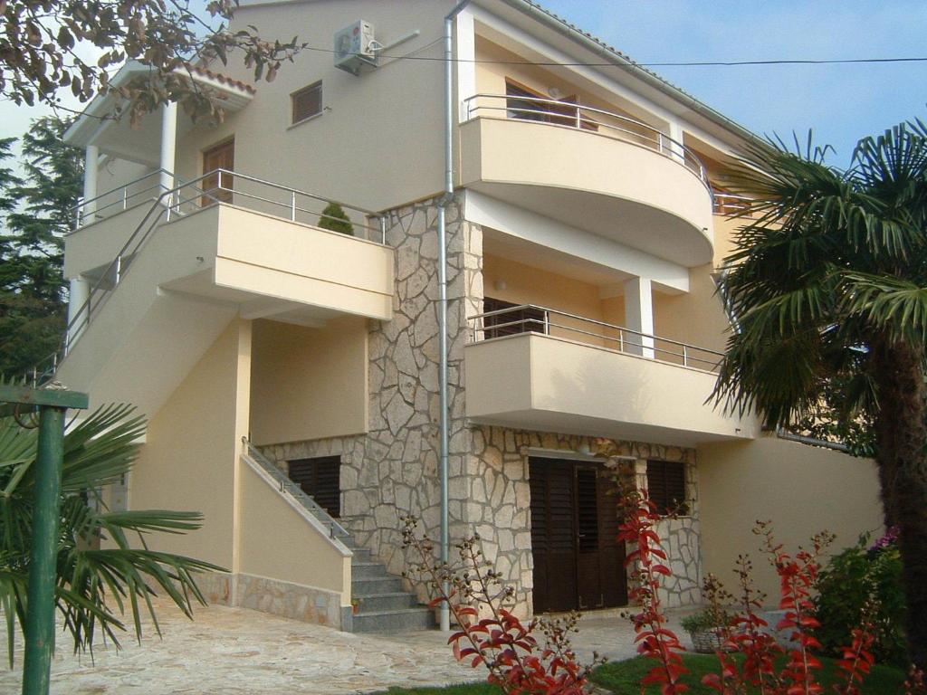 a building with two balconies and a palm tree at Apartments Tomic in Premantura