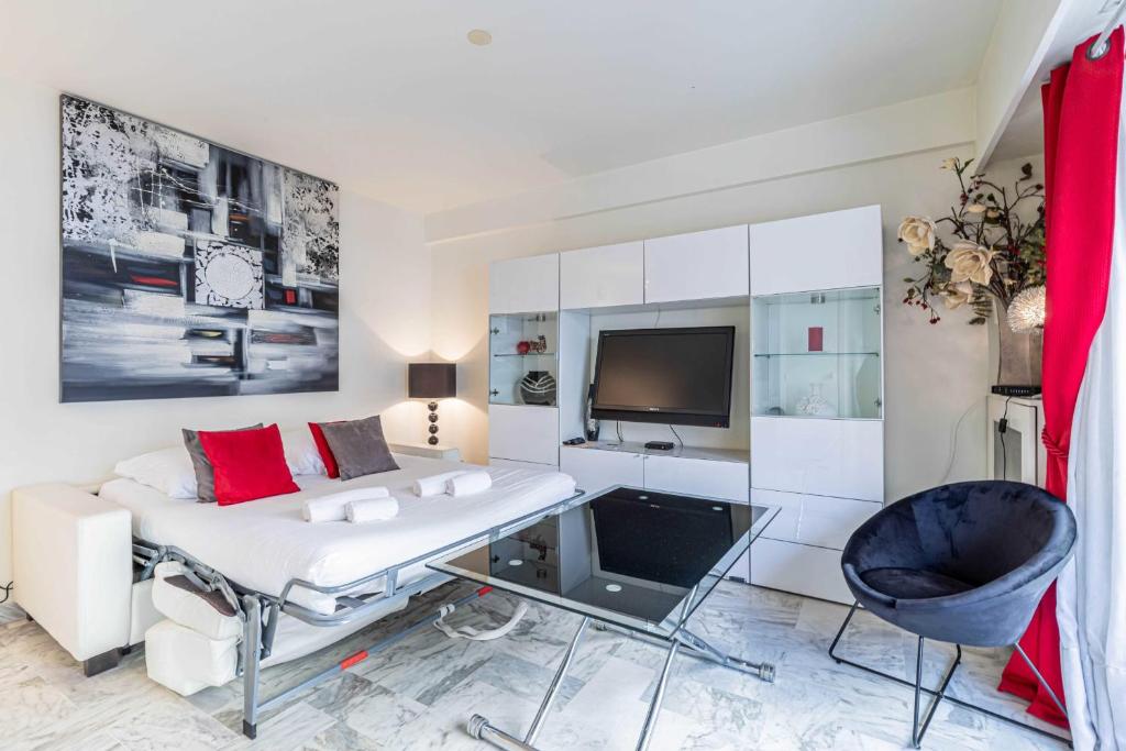 ein Wohnzimmer mit einem weißen Sofa und einem TV in der Unterkunft Cozy studio in the heart of Cannes - Near sea in Cannes