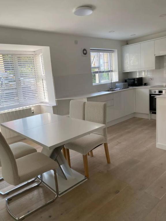 uma cozinha branca com uma mesa e cadeiras brancas em Spacious and Cosy 2 Bedroom Flat in Bermondsey em Londres