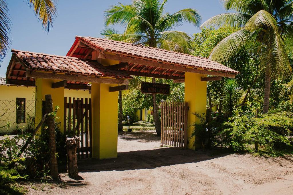 una casa amarilla con una puerta y palmeras en Pousada Vida Mar en Barra Grande