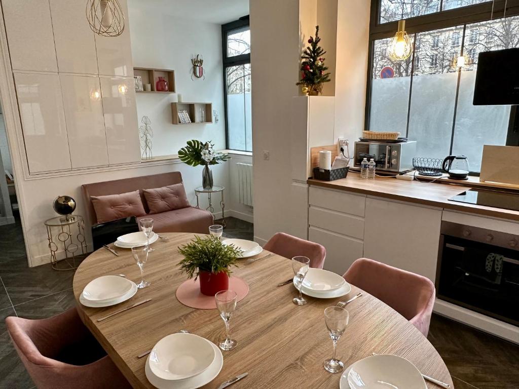 - une table à manger avec des assiettes et des verres à vin dans l'établissement Logement GUÉNOT pour 5 personnes sur Paris 11, à Paris