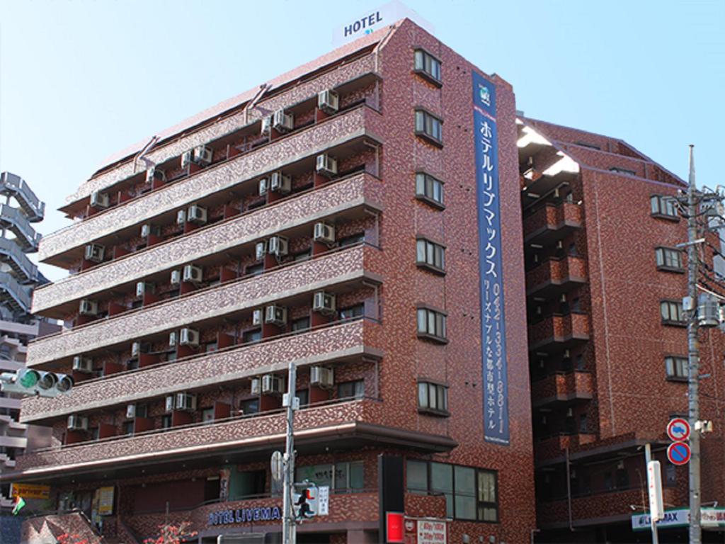 a tall red brick building with a sign on it at HOTEL LiVEMAX BUDGET Fuchu in Fuchu