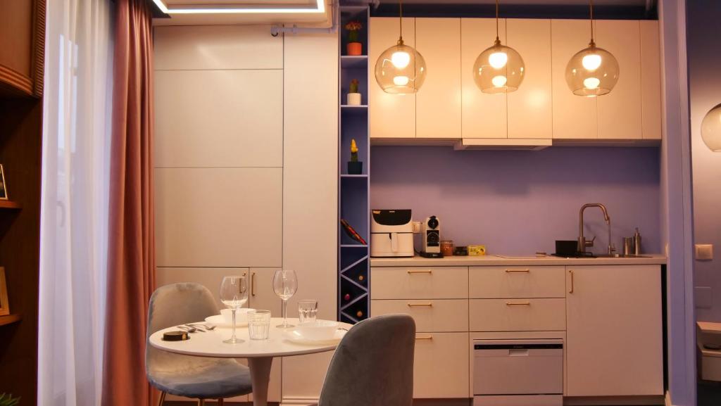 una cocina con mesa y sillas y una cocina con armarios blancos. en Downtown Italian Studio en Bucarest