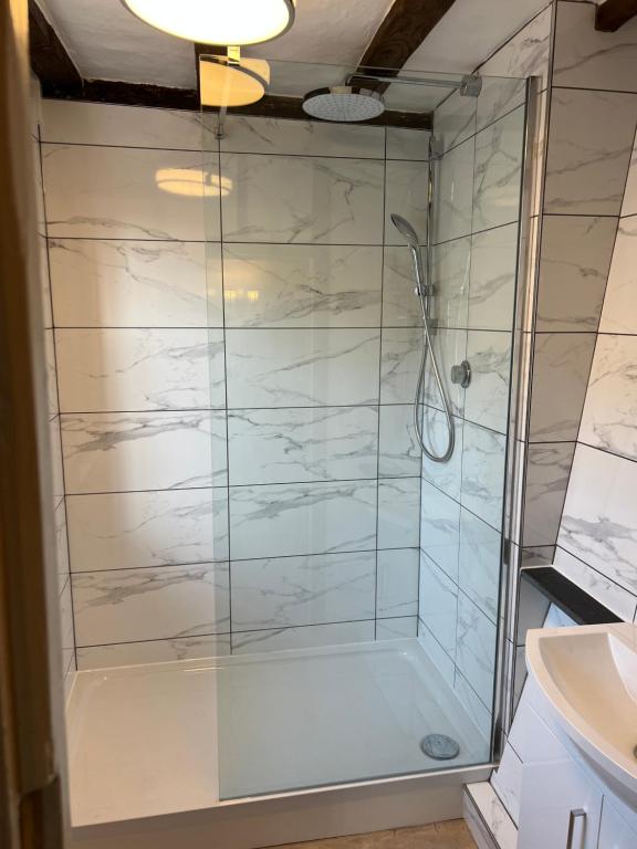 a shower with a glass door in a bathroom at Sutherland House in Southwold