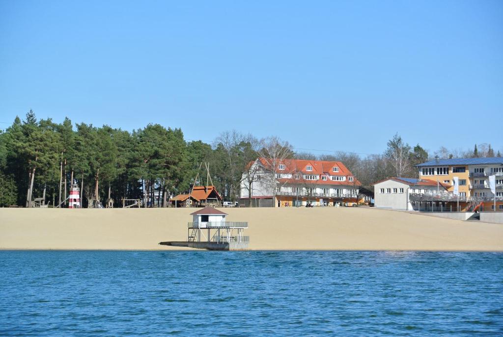 ein großer Sandstrand mit einem Boot im Wasser in der Unterkunft Bernsteinsee Hotel in Sassenburg