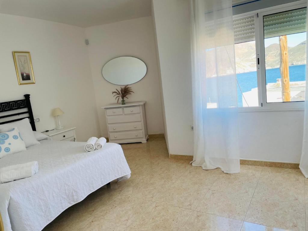 a bedroom with a bed and a mirror and a window at Apartamentos Dulcemar Frente al Mar con zona SPA in San José