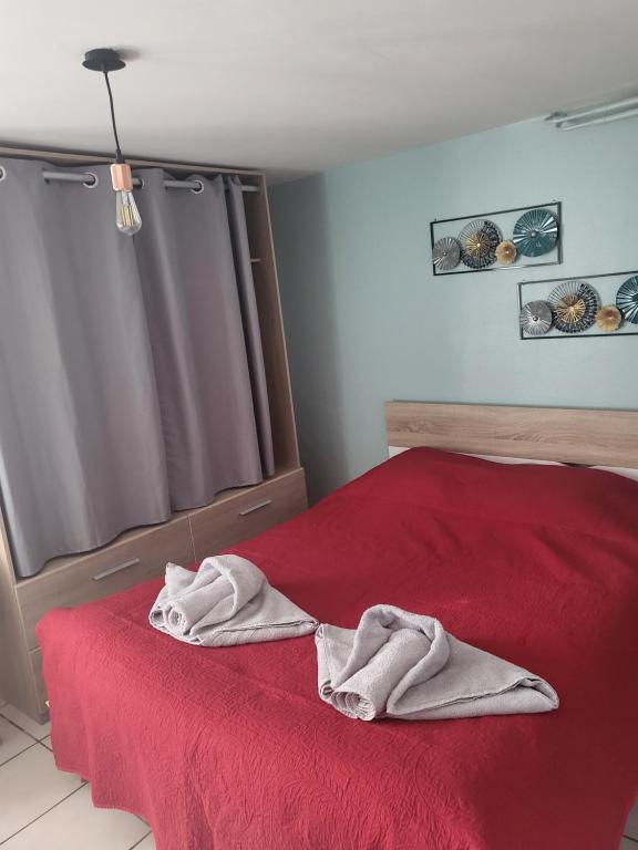 a bedroom with a red bed with towels on it at La Villa du MOULIN DE MADAME in Bias