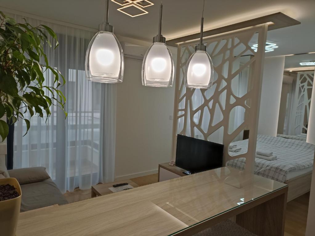 uma sala de estar com uma mesa e três luzes pendentes em Galija apartment em Belgrado