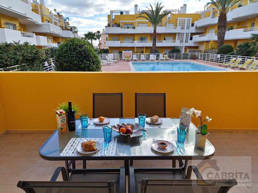 een tafel met eten en drinken op een balkon met een zwembad bij Casa dos Peixinhos T1 by YHA in Conceição