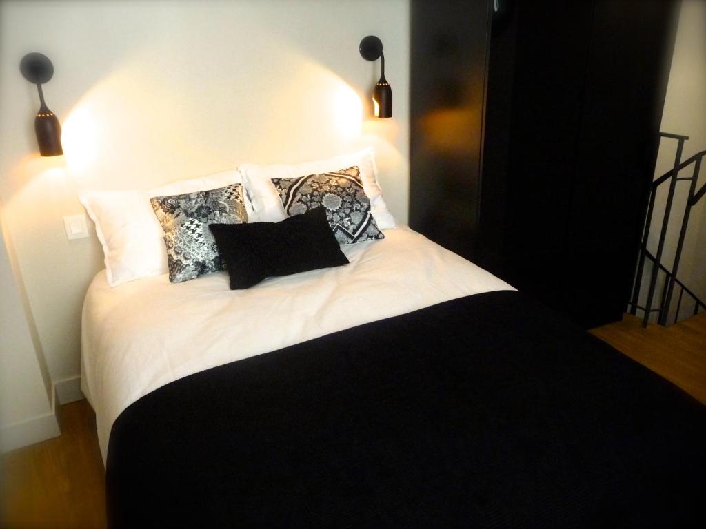 Una cama blanca y negra con almohadas. en Duplex de charme au Coeur de Montmartre, en París