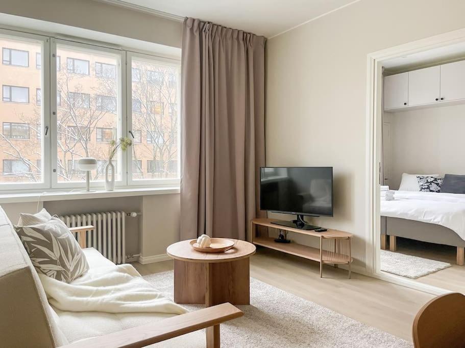 a white living room with a bed and a television at Central 1BR next to the park in Helsinki