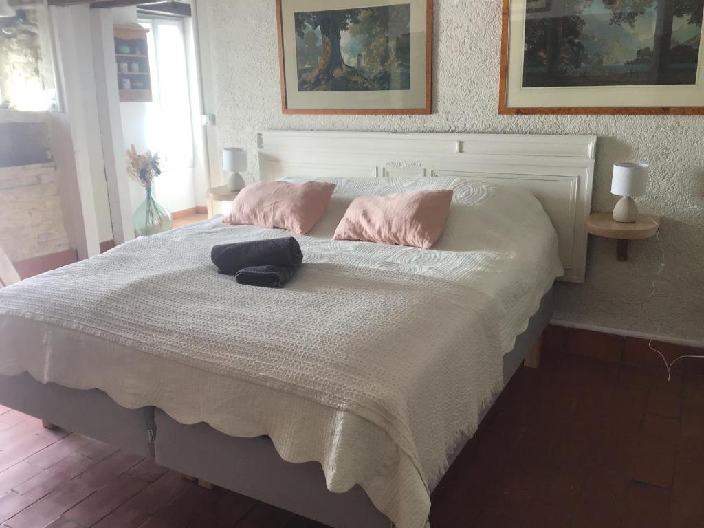 uma cama com almofadas cor-de-rosa e um chapéu em Mas de Bruget em Catus