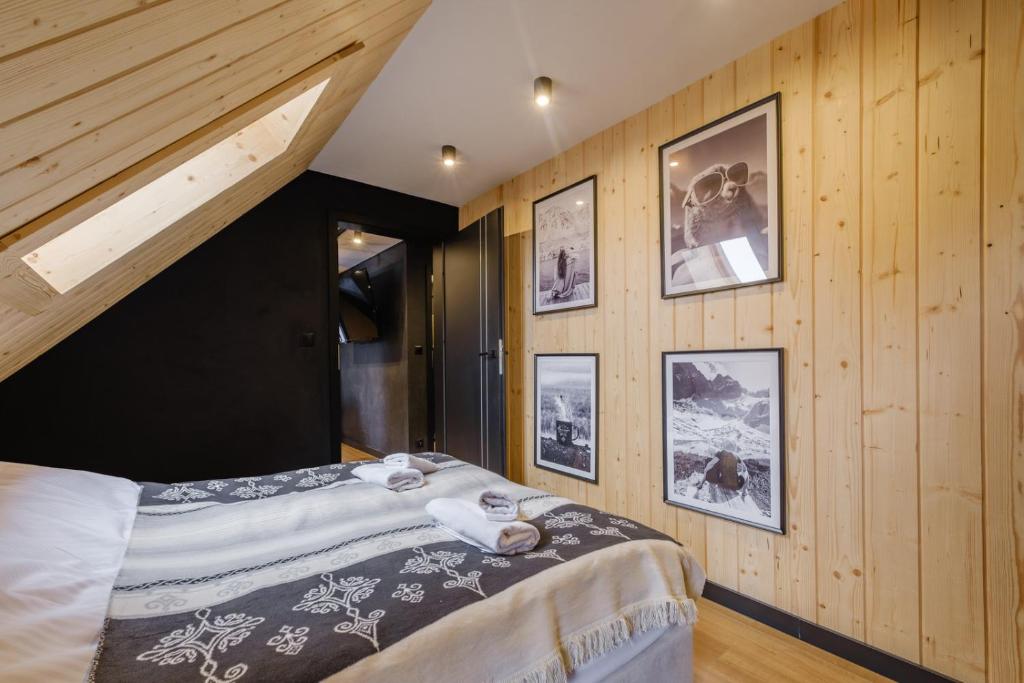 1 dormitorio con 1 cama y cuadros en las paredes en Villa 84 & Apartments Jacuzzi & Sauna en Zakopane