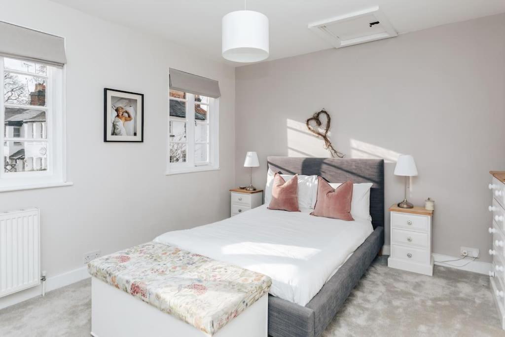 a bedroom with a white bed with a bench at the end of it at Chalk house - Pet friendly in Henley on Thames