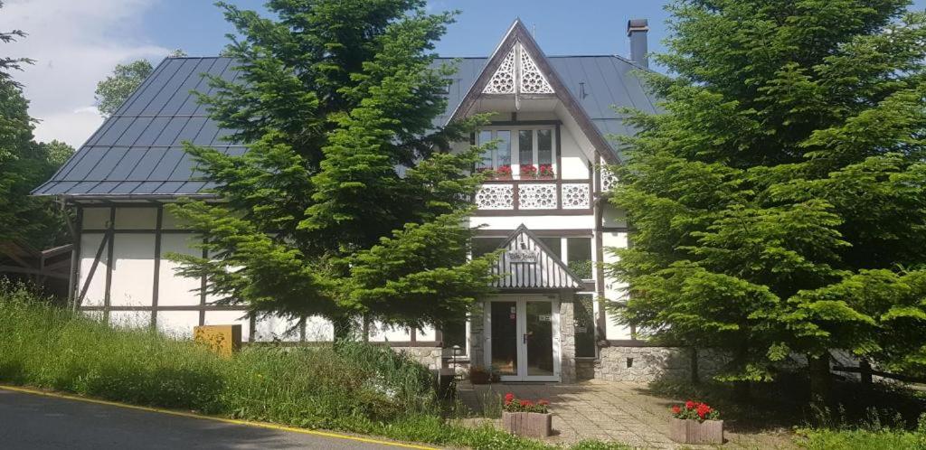 una casa blanca con techo negro en Vila Jedľa en Vysoké Tatry