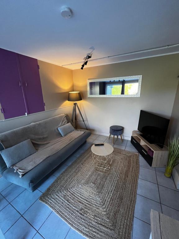 un soggiorno con divano e tavolo di Maison confortable et bien équipée entre Caen et Bayeux, proche plages du débarquement a Loucelles