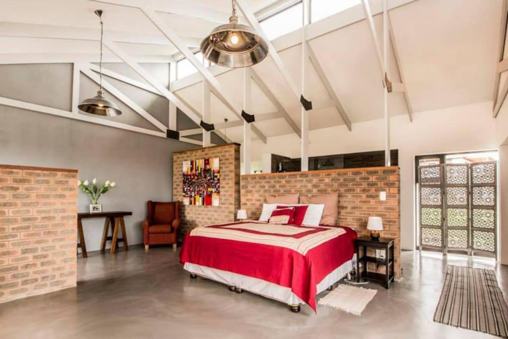 1 dormitorio con 1 cama grande y pared de ladrillo en Bromley loft en Port Alfred