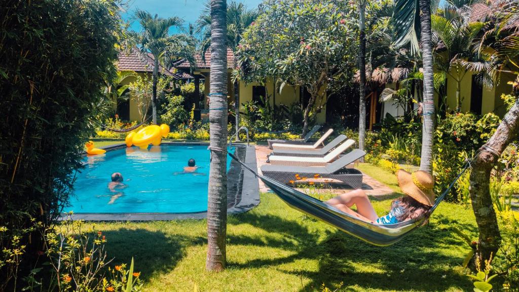 a group of people in a hammock in a pool at Arco Iris Boutique Hotel & Restaurant in Candidasa