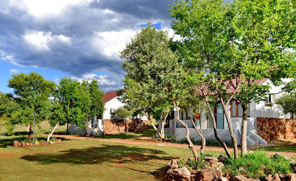 un groupe d'arbres dans une cour à côté d'un bâtiment dans l'établissement Thanda Manzi Country Hotel, à Centurion
