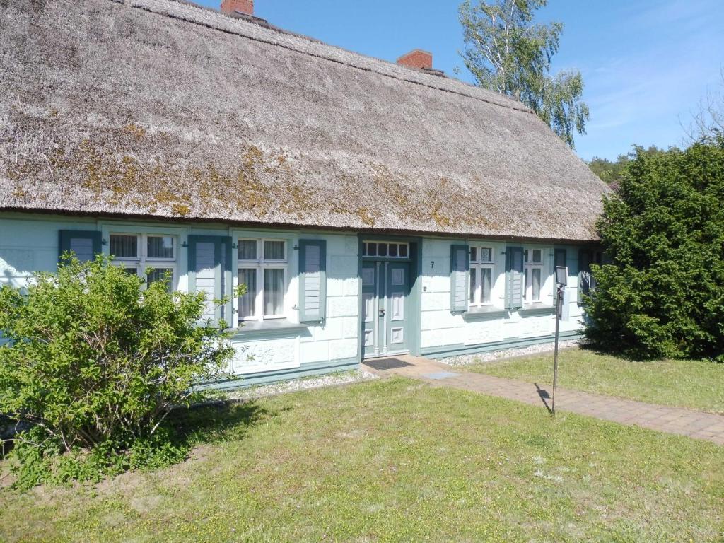 a white house with a thatched roof and a yard at Reetgedecktes Ferienhaus Ulrichshorst in Ulrichshorst