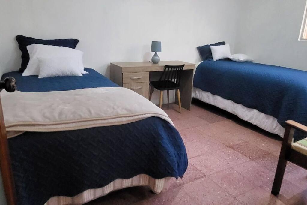 1 Schlafzimmer mit 2 Betten, einem Schreibtisch und einem Stuhl in der Unterkunft Casa para viajes de descanso o de negocios in Quetzaltenango