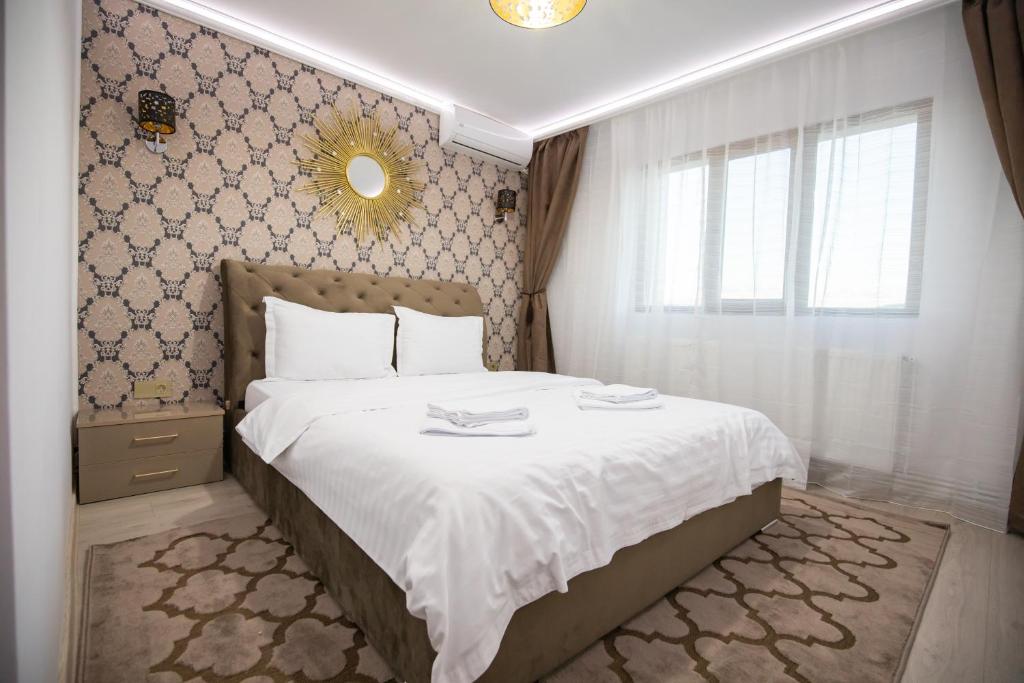 a bedroom with a bed with white sheets and a mirror at Apartament Gold in Târgu Ocna