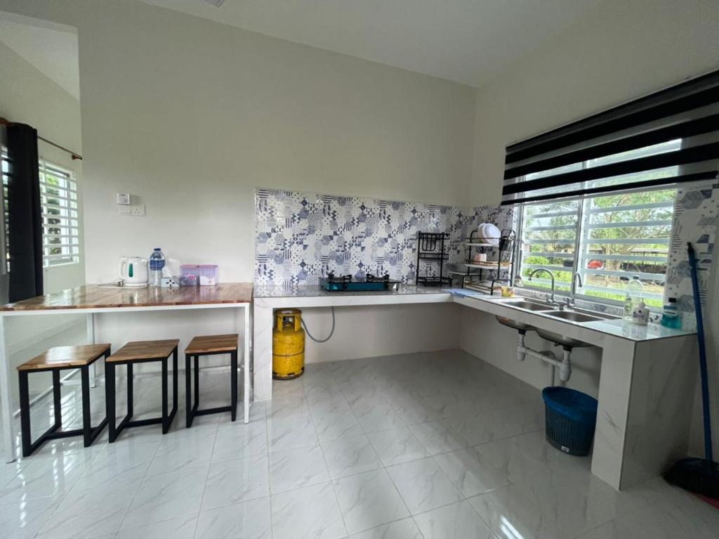 a kitchen with a sink and a counter with stools at Inap desa homestay batu buruk in Kuala Terengganu