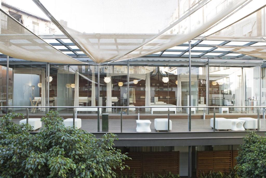 un grand bâtiment en verre avec des tables et des chaises blanches dans l'établissement Hospes Palau de La Mar, Valencia, a Member of Design Hotels, à Valence