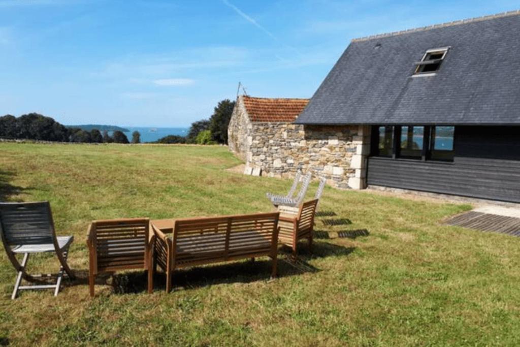 dos bancos sentados en un campo al lado de un edificio en Large farmhouse with garden and sea view for 8 people en Locquénolé