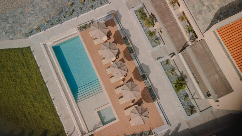 an overhead view of a swimming pool with chaise lounge chairs at Marble Luxury Suites in Karteros