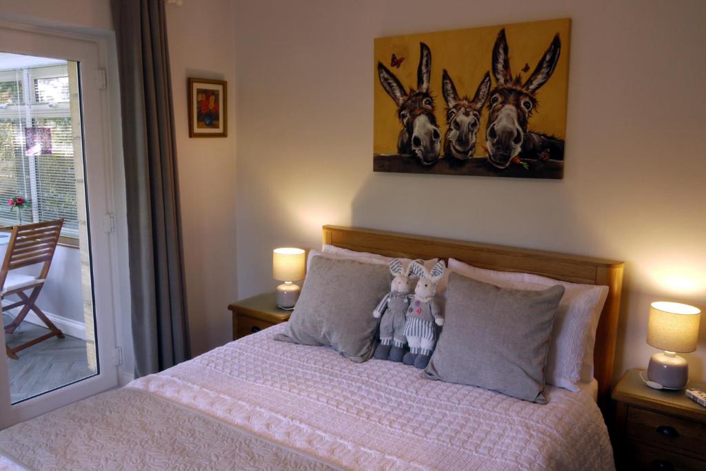 a bedroom with a bed with two stuffed animals on it at Cosy Stone Cottage, The Bungalow Perrotts Brook in Cirencester