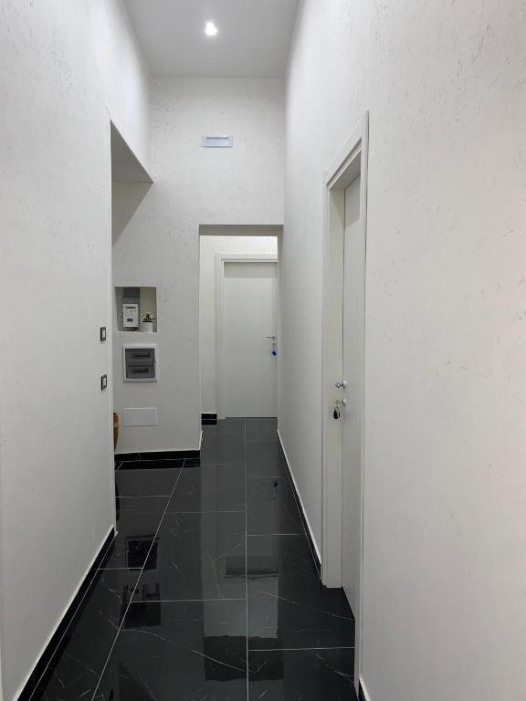 a hallway with white walls and a black tile floor at Savastano house in Naples