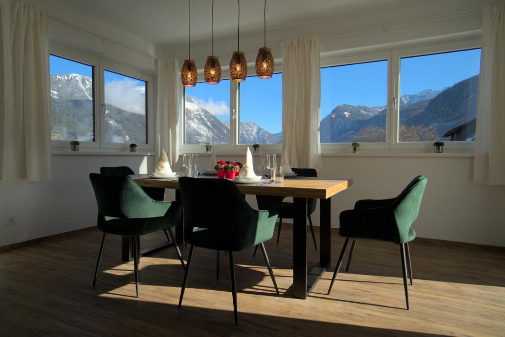 a dining room with a table and chairs and windows at Dangos Mountainview Gosau in Gosau