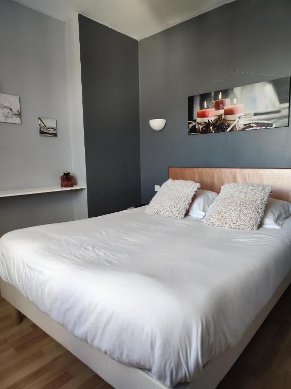 una camera da letto con un grande letto con lenzuola bianche di LE SPORTING a Beaumont-sur-Lèze