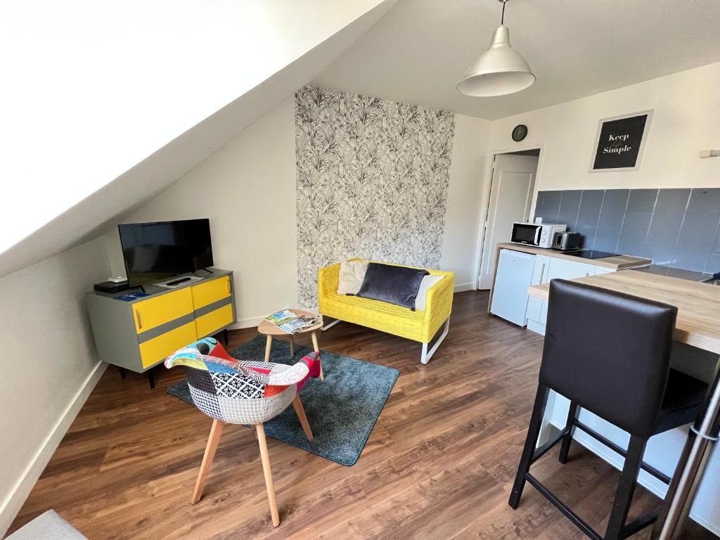 a living room with a yellow chair and a kitchen at La petite Venise du Loir in Vendôme