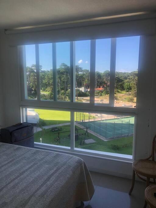 1 dormitorio con ventana grande con vistas a una pista de tenis en Inolvidable paz y belleza, en Punta del Este