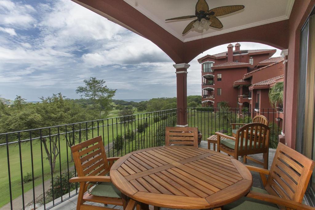 een veranda met een houten tafel en stoelen op een balkon bij Bougainvillea 9305 Luxury Apartment - Reserva Conchal in Playa Conchal