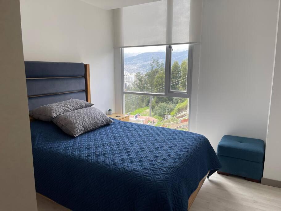 a bedroom with a blue bed with a large window at Dpo 2 dorm(parqueadero wifi Netflix)vista pan. UIO in Quito