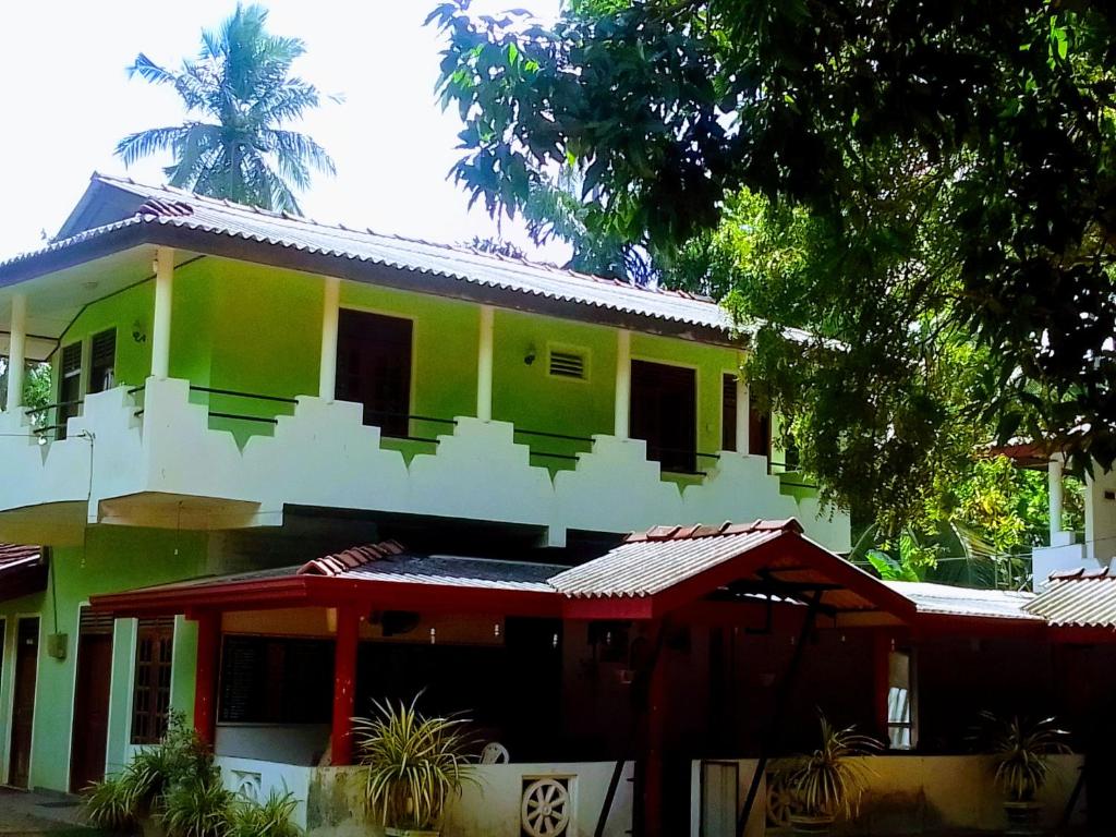 a green and white house with a palm tree at New Green Garden Hotel & Safari in Tissamaharama