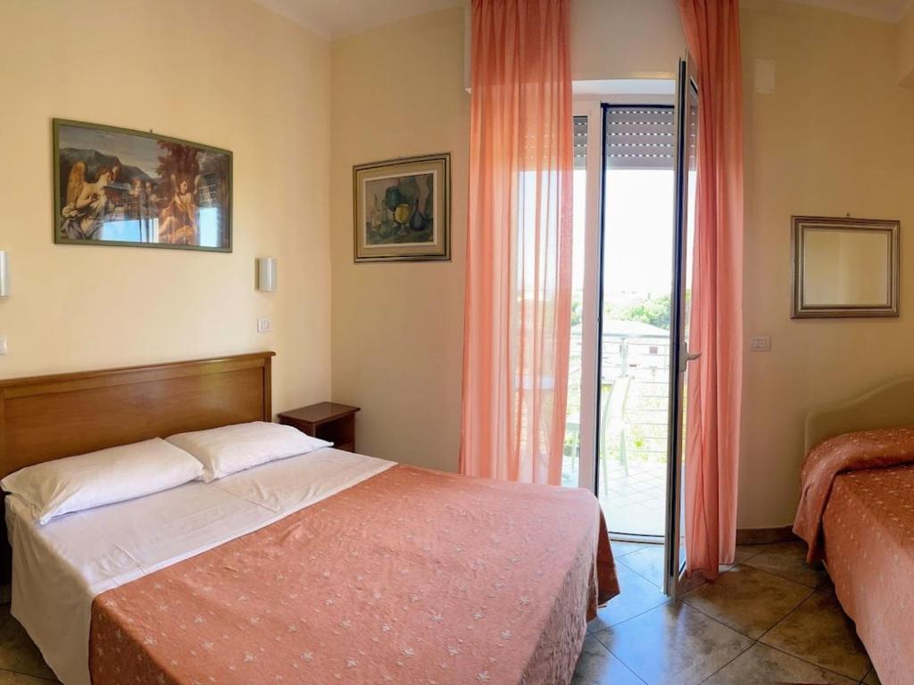 een slaapkamer met een bed en een glazen schuifdeur bij Hotel Franca in Milano Marittima