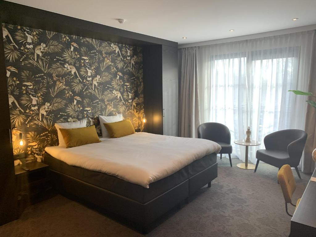 1 dormitorio con 1 cama grande y papel pintado con motivos florales en Van Der Valk Hotel Brugge Oostkamp, en Oostkamp