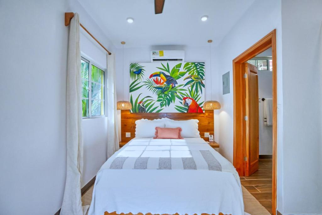 a bedroom with a white bed and a painting on the wall at Villa Massis Luxury Villas in San Ignacio